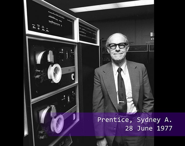 Sydney A Prentice poses next to a computer in 1977